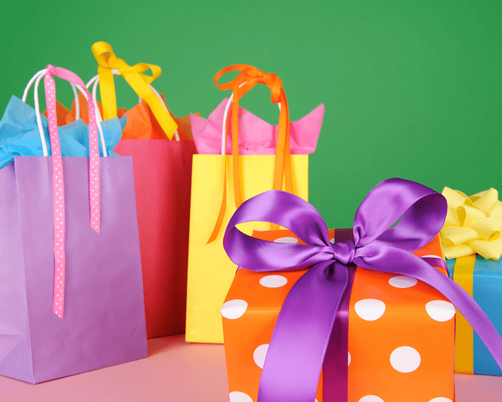 Gilmore Girls Gift Ideas. Brightly colored purple, red and yellow gift bags in front of a green background